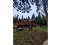 Beautiful log home with a large deck surrounded by lush greenery and tall trees at 8905 Carol Ln, Conifer, CO 80433