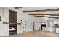 Open-concept living space with vaulted ceilings, exposed beams, fireplace, and a view into the updated kitchen at 2665 Juilliard St, Boulder, CO 80305