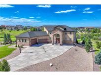 Stunning two-story home with a stone facade, lush landscaping, and a large driveway with basketball court at 7343 Upton Ct, Castle Rock, CO 80104