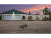 A home with a large garage and interesting privacy wall and arched entry at dusk at 15623 Degaulle Cir, Brighton, CO 80603
