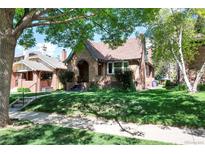 Charming brick home with a well-manicured lawn and mature trees providing shade and curb appeal at 766 Monroe St, Denver, CO 80206