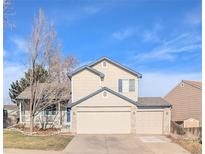 Charming two-story home with a spacious three car garage, and manicured lawn against a bright blue sky at 4395 S Gibraltar St, Centennial, CO 80015