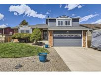 Charming home showcasing a well-maintained front yard, complemented by blue accents and a two-car garage at 3680 S Gibralter Cir, Aurora, CO 80013