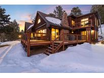Two-story home with large deck and snowy landscape at 20242 Cypress Dr, Morrison, CO 80465