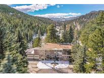 Mountain home featuring a large driveway and attached garage, surrounded by lush evergreen trees at 31453 Upper Bear Creek Rd, Evergreen, CO 80439