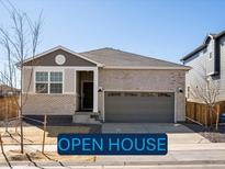 Charming single-story home with light brick, a two-car garage, and well-maintained landscaping at 6092 Corral St, Brighton, CO 80601