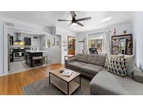 Open-concept living room with hardwood floors, a gray sofa, and kitchen view creates a welcoming space at 3730 Lowell Blvd, Denver, CO 80211