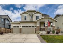 Two-story home with three-car garage, stone accents, landscaped front yard, and an American flag at 11657 Olathe St, Commerce City, CO 80022