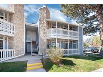 Charming condo building with multiple balconies, stone accents, and mature trees at 8335 Fairmount Dr # 7-208, Denver, CO 80247