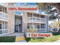 Renovated condo building featuring a one-car garage, stone accents, and outdoor stairways with white banisters at 8335 Fairmount Dr # 7-208, Denver, CO 80247