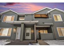 Townhome exterior featuring gray siding, stone accents, and a shared covered entryway with unit numbers under a colorful sunset sky at 912 S Yampa St # 208, Aurora, CO 80017