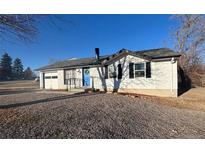 Charming home featuring a blue front door, light brick, and an attached garage at 7604 Reed St, Arvada, CO 80003