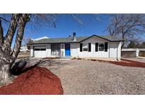 Charming brick home with a blue front door and well-maintained landscaping at 7604 Reed St, Arvada, CO 80003