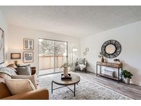 Bright living room with a decorative rug and access to a balcony with sliding glass doors at 10211 Ura Ln # 7-204, Thornton, CO 80260