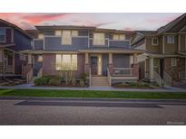 Inviting two-story townhome with brick accents, covered porch, and manicured lawn at 5983 Fulton St, Denver, CO 80238