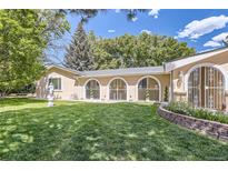 Charming house backyard with lush green grass and unique architectural arched windows at 8220 Lamar Cir, Arvada, CO 80003