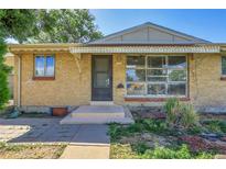Charming brick home featuring front door, concrete steps, and large picture window at 9095 Beechwood Dr, Thornton, CO 80229