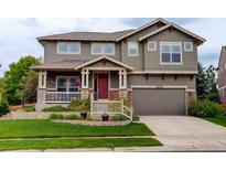 Charming two-story home with a well-maintained lawn, inviting porch, and an attached two-car garage at 14200 W 86Th Pl, Arvada, CO 80005