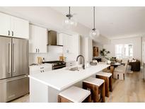 Bright kitchen boasts stainless appliances, a center island, white shaker cabinets, and pendant lighting at 8260 E 36Th Ave # 30, Denver, CO 80238