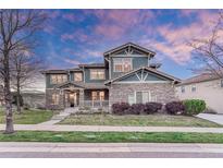 Charming two-story home with a stone facade, covered porch, and well-manicured lawn at dusk at 10459 Rivington Ct, Lone Tree, CO 80124
