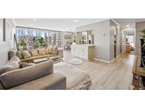 Bright living room with large windows, hardwood floors, and an open floor plan to the dining area at 955 Eudora St # 307E, Denver, CO 80220
