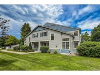 Charming townhome with blue accents, lush lawn, and mature trees under a bright blue sky at 1419 Red Mountain Dr # 126, Longmont, CO 80504