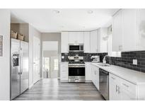 Modern kitchen with white cabinets, stainless steel appliances, and dark tile backsplash at 1531 W Dakota Ave, Denver, CO 80223