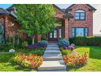 Beautiful brick home featuring a landscaped front yard with colorful flowers and a charming entrance at 5672 S Nome St, Englewood, CO 80111