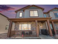 Charming two-story home featuring a covered front porch with stone accents and stylish gray siding, and beautiful dusk sky at 20932 E 60Th Ave, Aurora, CO 80019
