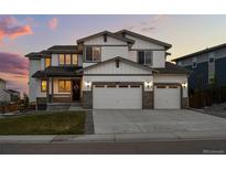 Beautiful two-story home boasting a three-car garage, manicured lawn, and classic architectural details at 6696 Kenzie Cir, Castle Pines, CO 80108