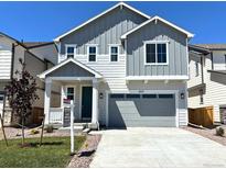 Charming two-story home featuring a gray exterior, well-maintained lawn, and a two-car garage at 9277 Truckee Ct, Commerce City, CO 80022