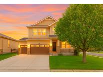 Beautiful two-story home featuring an attached garage, lovely porch, well-manicured lawn, and professional landscaping at 10995 Quintero St, Commerce City, CO 80022