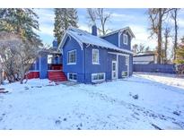 Charming blue home with red-painted porch steps, snow-covered yard, and mature trees at 5725 W Mississippi Ave, Lakewood, CO 80226