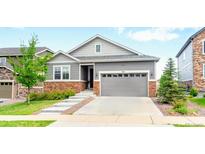 Charming gray two-story home with stone accents, a well-manicured lawn, and a two car garage at 7410 S Old Hammer Way, Aurora, CO 80016