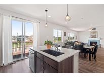 Open kitchen with island and stainless appliances, and a seamless flow to an outdoor deck at 7410 S Old Hammer Way, Aurora, CO 80016