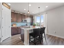Modern kitchen with stainless steel appliances, center island, and beautiful blue backsplash at 7410 S Old Hammer Way, Aurora, CO 80016