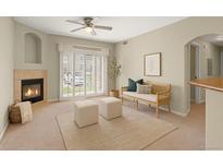 Bright living room featuring a fireplace, ceiling fan, neutral carpet, and sliding glass doors at 7440 S Blackhawk St # 104, Englewood, CO 80112