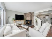 Cozy living room features a stone fireplace, modern furnishings and a large window for ample natural light at 8873 Yukon St, Broomfield, CO 80021