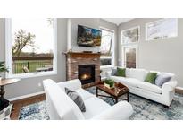 Cozy living room with a brick fireplace, white couches, and scenic views through large windows at 787 Kendall Ct, Lakewood, CO 80214