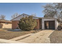 Charming single-story brick home with a carport and mature landscaping on a sunny day at 6032 Estes St, Arvada, CO 80004