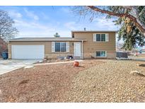 Charming tan two-story home featuring white window trim, a two car garage, and decorative stone landscaping at 2911 S Olathe Way, Aurora, CO 80013