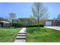 Charming home featuring a well-manicured front yard, lush lawn, and a welcoming walkway leading to the front door at 12154 W Exposition Dr, Lakewood, CO 80228