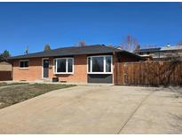Charming brick home with a well-manicured lawn, driveway, and a wooden privacy fence at 3675 W Amherst Ave, Denver, CO 80236