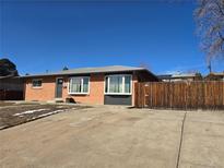 A well-maintained brick house with a wooden privacy fence and mature landscaping at 3675 W Amherst Ave, Denver, CO 80236