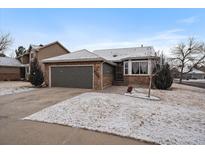 Charming single-Gathering home featuring a brick and siding exterior with attached two-car garage and snow-covered yard at 6689 Kendrick Dr, Arvada, CO 80007