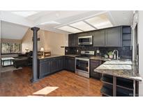 Well-lit kitchen featuring dark cabinets, stainless steel appliances, granite countertops, and sleek backsplash at 9400 E Iliff Ave # 37, Denver, CO 80231