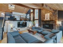 Inviting living room featuring stone fireplace, wood beamed ceiling and comfortable seating area at 45 Oak Way, Evergreen, CO 80439