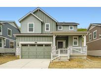 Charming two-story home featuring a covered porch, two-car garage, and appealing sage green siding at 7367 S Yank Ct, Littleton, CO 80127