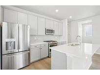 Modern kitchen featuring stainless steel appliances, a subway tile backsplash, and white countertops at 21021 E 63Rd Dr, Aurora, CO 80019