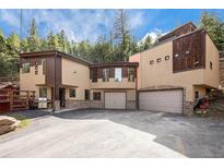 A contemporary two-story home nestled in a wooded setting, featuring a large driveway and attached two-car garage at 30174 Glen Eyrie Dr, Evergreen, CO 80439